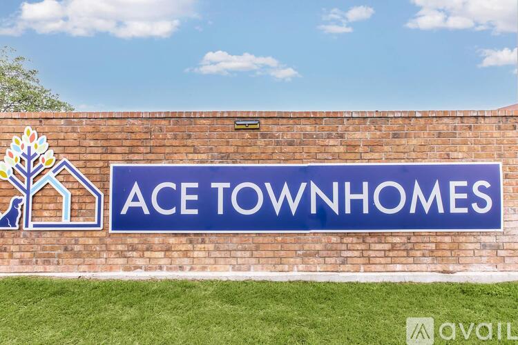 A sign that says Ace Townhomes on a brick wall.