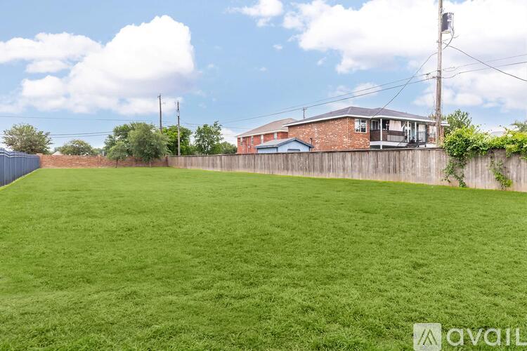 A large grassy area with a house and fence in the background.