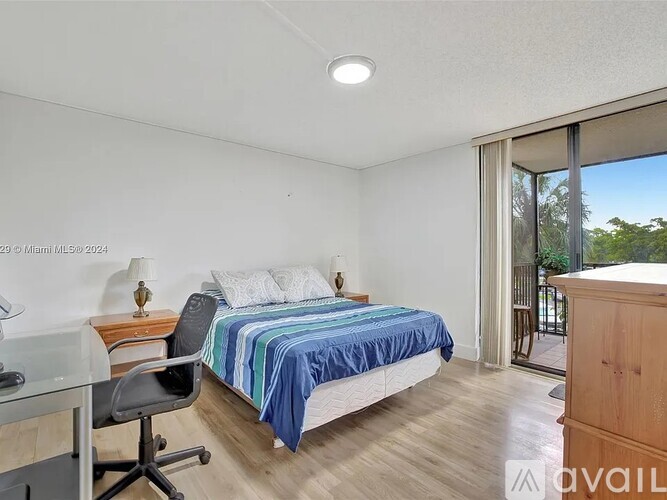 A bedroom with a bed, desk, chair, and sliding glass doors.