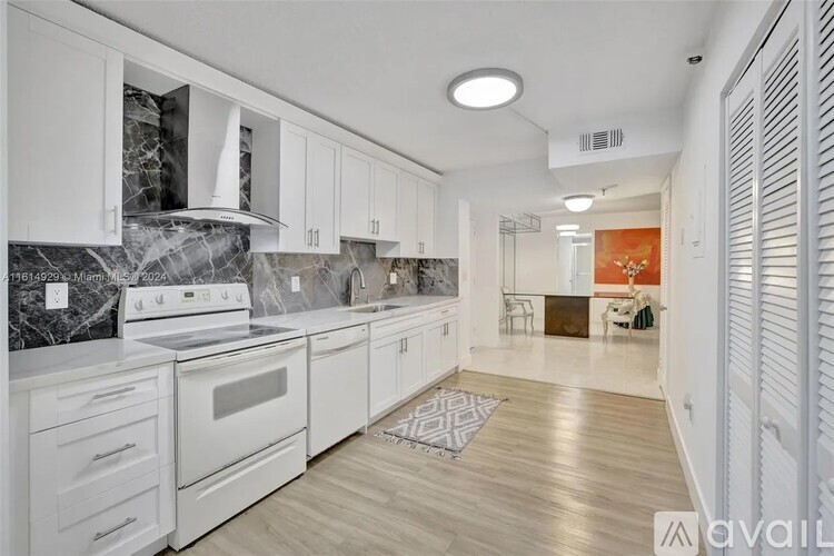 A kitchen with white cabinets and a marble backsplash.