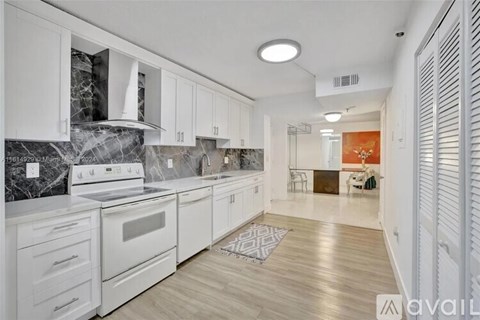 A kitchen with white cabinets and a marble backsplash.