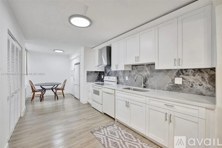 A kitchen with white cabinets and a marble backsplash.