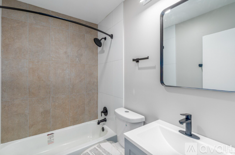 A bathroom with a white sink, toilet, and a tiled shower.