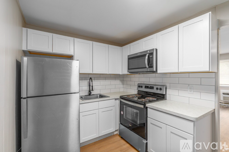 A kitchen with white cabinets and a stainless steel refrigerator.