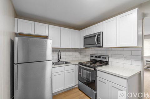 A kitchen with white cabinets and a stainless steel refrigerator.