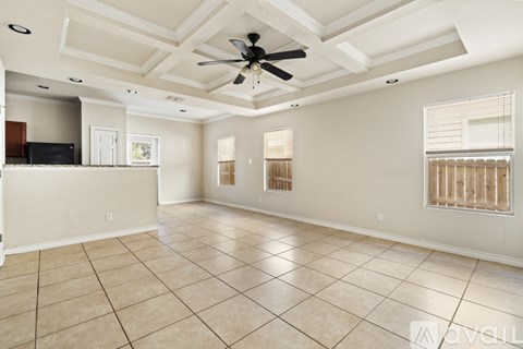 A spacious living room with a ceiling fan and tiled flooring.