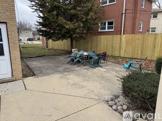 A patio with a table and chairs is surrounded by a wooden fence.
