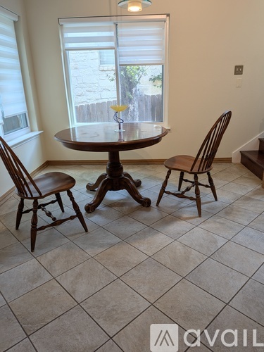A dining room with a round table and two chairs.
