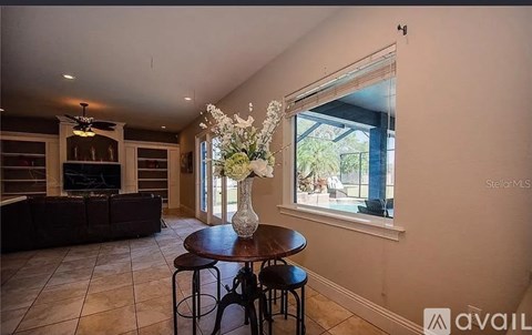 A living room with a brown sofa and a table with a vase of flowers on it.