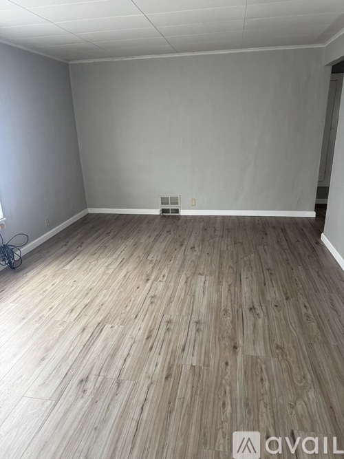 A room with wooden flooring and white walls.
