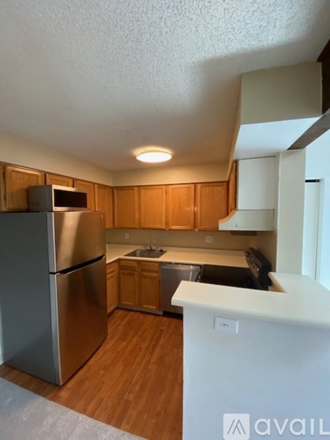 A kitchen with wooden cabinets and a stainless steel refrigerator.