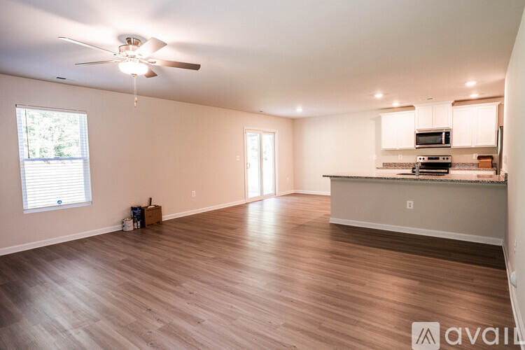 A spacious living room with a ceiling fan and hardwood flooring.