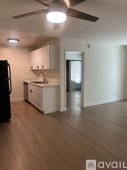 A kitchen with a refrigerator, sink, and cabinets.