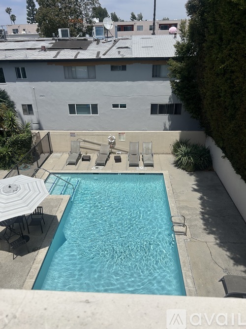 A swimming pool in a backyard with a patio table and chairs.