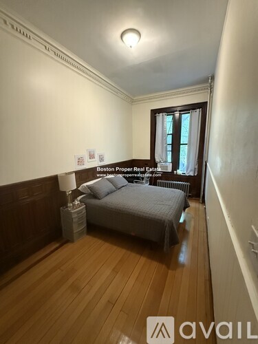 A bedroom with a bed, nightstand, and window.
