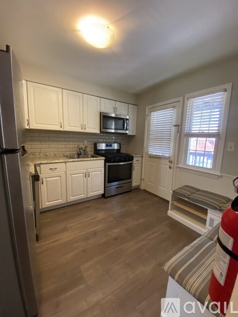 A kitchen with wooden floors and white cabinets.