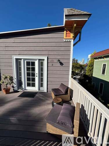 A deck with a bench and a chair is in front of a grey house.