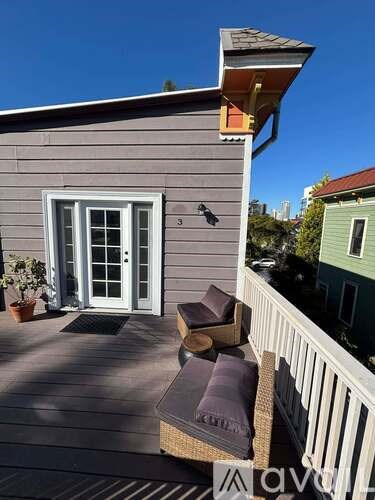 A deck with a bench and a chair is in front of a grey house.