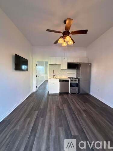 A spacious room with a ceiling fan and a television mounted on the wall.