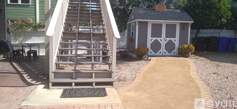 A wooden staircase with a metal grate at the bottom leads up to a small white building.