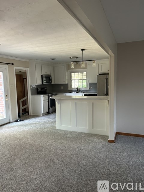 A kitchen with white cabinets and a grey carpet.