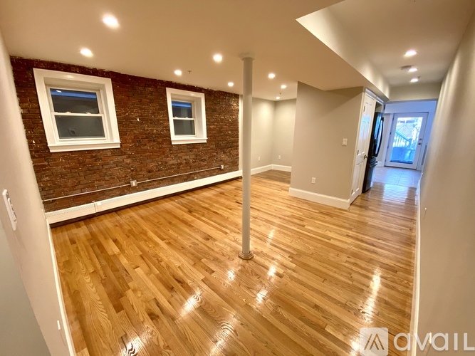 A room with wooden flooring and a brick wall.