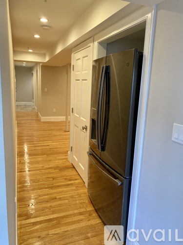 A kitchen with a stainless steel refrigerator and wooden floors.
