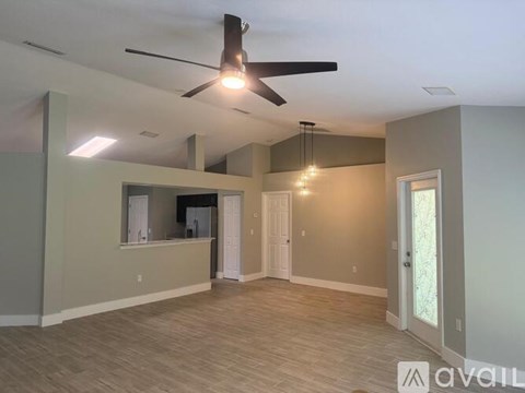 A spacious room with a ceiling fan and lighting fixtures.