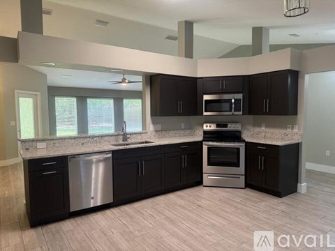 A kitchen with black cabinets and stainless steel appliances.