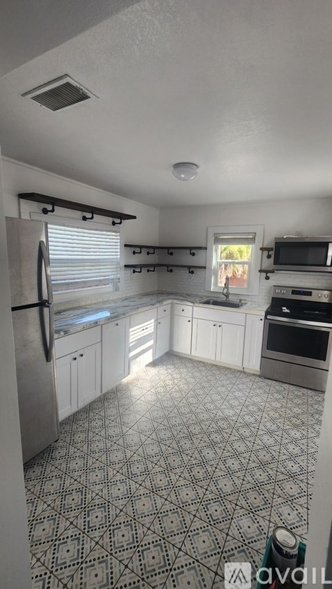 A kitchen with a patterned floor and white cabinets.