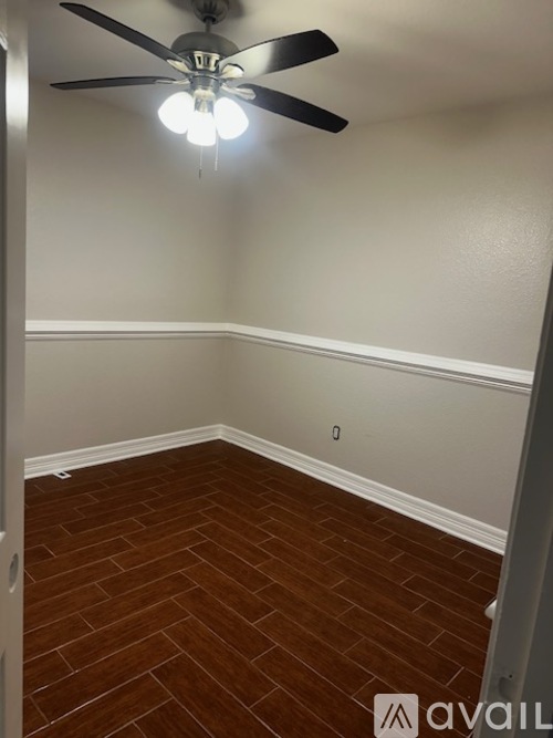 A room with a ceiling fan and wooden flooring.