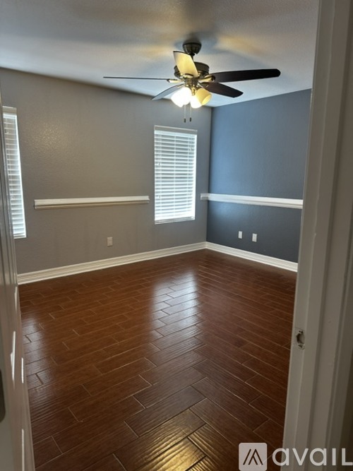 A room with a ceiling fan and wooden flooring.