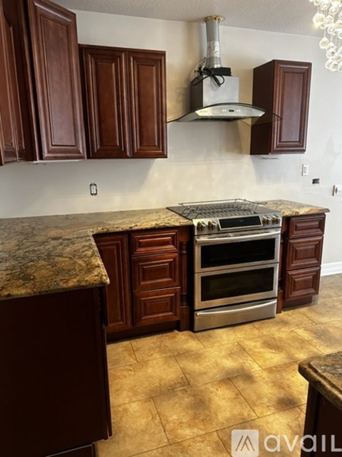 A kitchen with brown cabinets and a granite countertop.