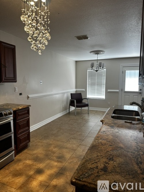 A kitchen with a granite counter top and a chandelier hanging from the ceiling.