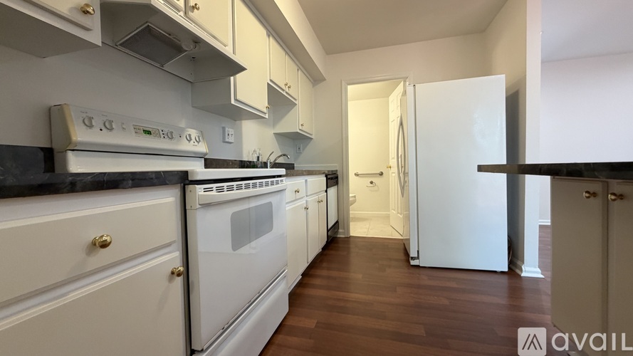 A kitchen with white appliances and wooden floors.