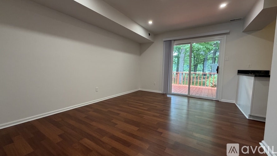 A room with wooden flooring and a large window overlooking a playground.
