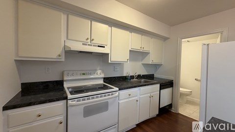 A kitchen with white cabinets and black countertops.