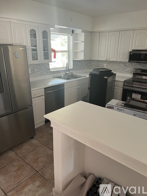A kitchen with a refrigerator, microwave, oven, and sink.