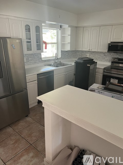 A kitchen with a refrigerator, microwave, oven, and sink.