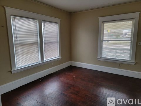 A room with two windows and wooden floors.