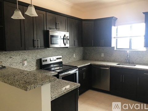 A kitchen with black cabinets and granite countertops.