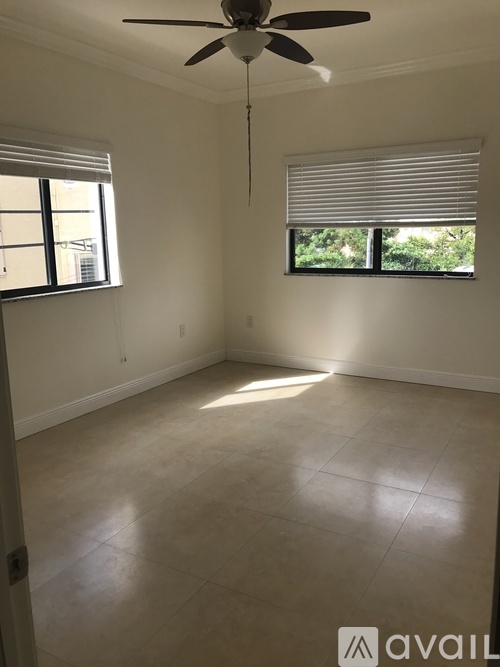 A room with a ceiling fan and two windows.