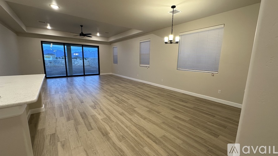 A spacious room with wooden flooring and a large window overlooking a snowy landscape.