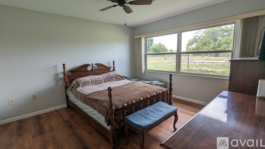 A bedroom with a large bed and a window overlooking a grassy area.