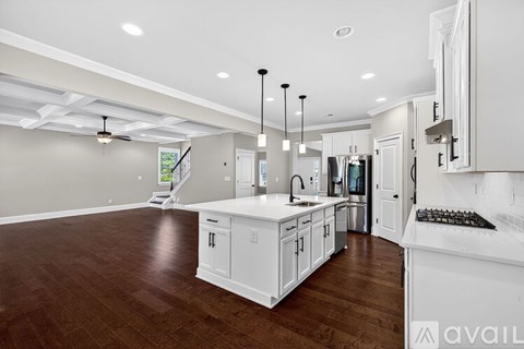 A spacious kitchen with white cabinets and a wooden floor.