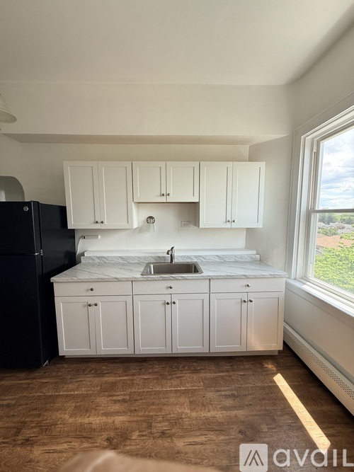 A kitchen with white cabinets and a black refrigerator.