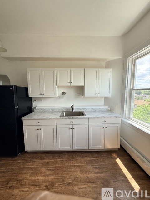 A kitchen with white cabinets and a black refrigerator.