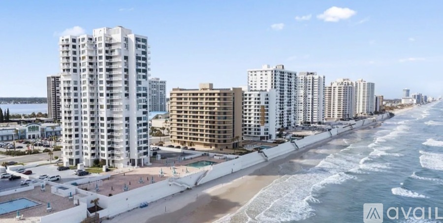 A row of beachfront condos with a pool in the foreground.