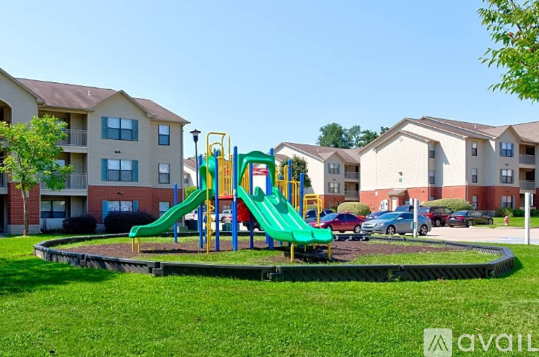 A playground with a green slide and a yellow structure in front of apartment buildings.