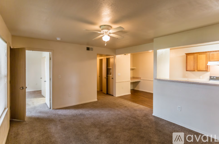 A room with a carpeted floor and a ceiling fan.